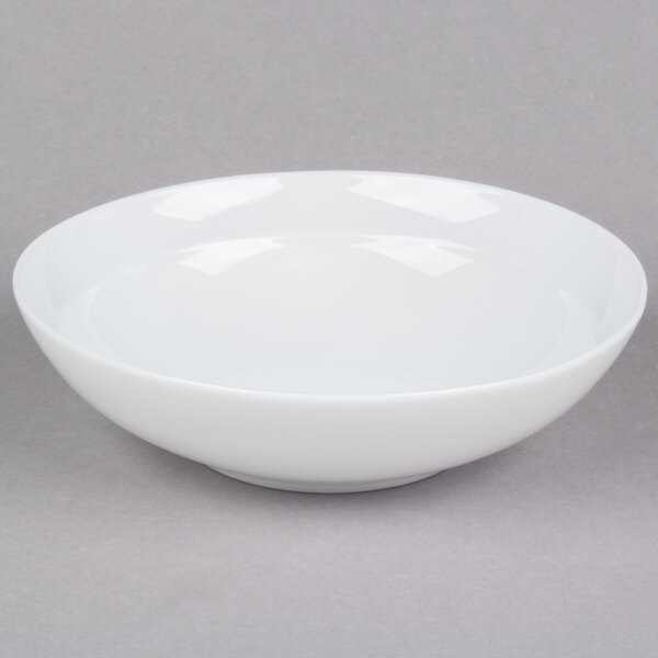 An Arcoroc white soup/cereal bowl on a gray surface.