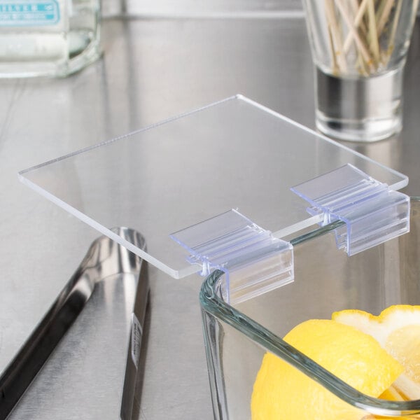 A glass container with a clear plastic lid holding lemons.