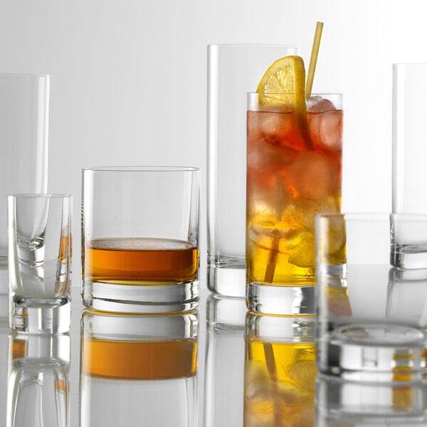 A group of Stolzle New York shot glasses with different colored drinks.
