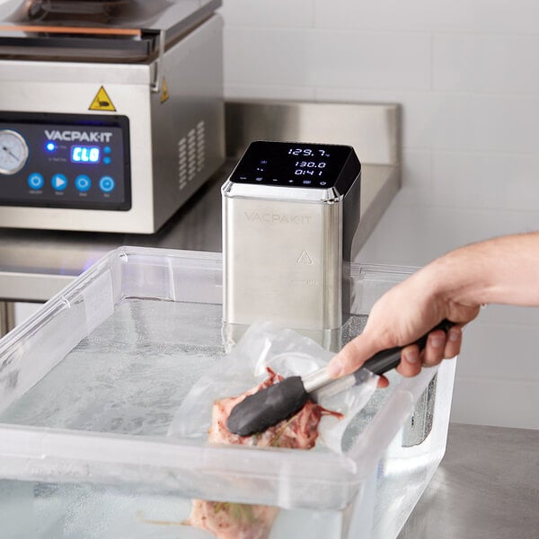 chef using tongs to place vacuum wrapped meat in a sous vide machine