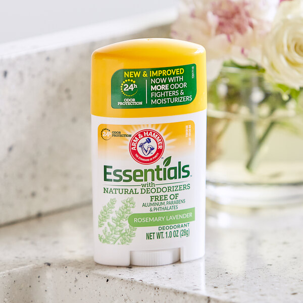 A white and yellow Arm & Hammer Essentials deodorant bottle with a label sitting on a counter.