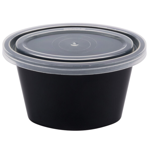 A Newspring black oval souffle container with a clear lid.