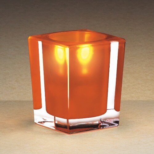 A Sterno orange and clear square liquid candle holder with a light inside holding a small orange candle.