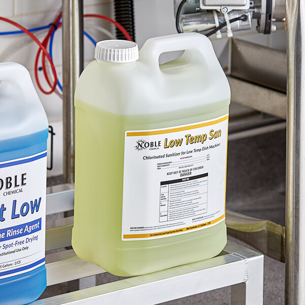 Two white plastic jugs of yellow Noble Chemical liquid sitting on a metal shelf.