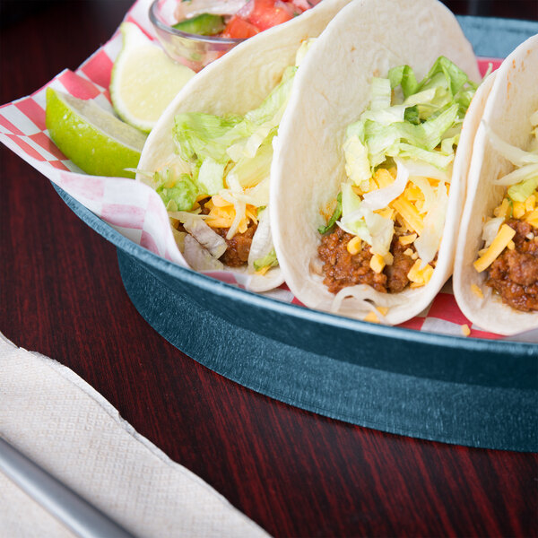 A plate of tacos served in a blueberry oval deli server on a table.