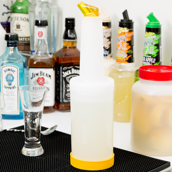 A close-up of a white Carlisle Store 'N Pour container with a yellow spout and cap on a counter.