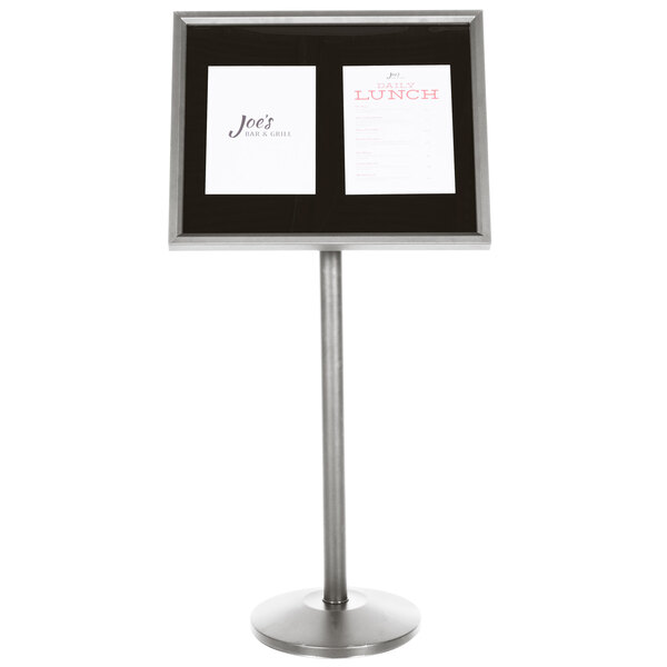 A black menu board with a silver pedestal frame holding neon markers.