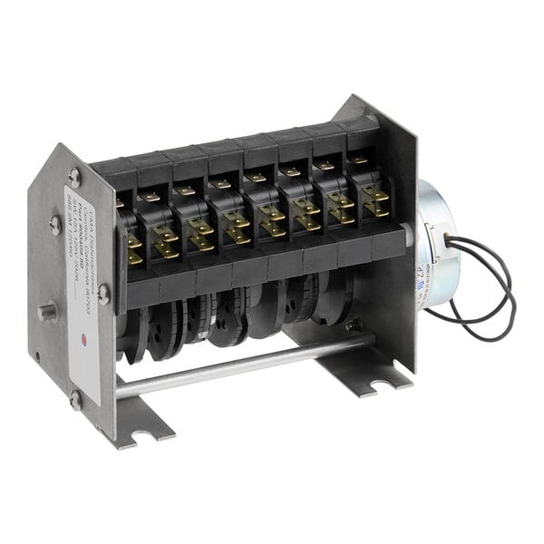 A metal and plastic electrical timer component with multiple connection terminals and a cylindrical motor housing, mounted on a metal frame.