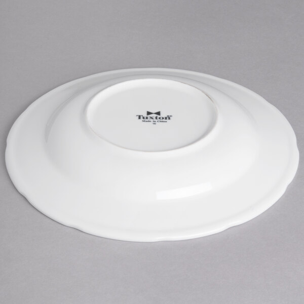 A white Tuxton china rim soup bowl with a small black logo on it.