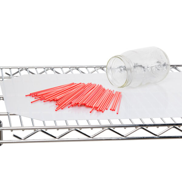 A glass jar of red straws on a Metro translucent shelf.