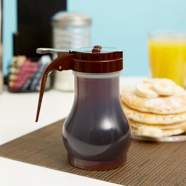 A brown Tablecraft syrup dispenser on a table with pancakes and bananas.