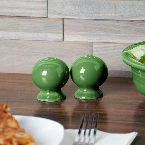 A table set with Fiesta Meadow salt and pepper shakers, pizza, and bowls.