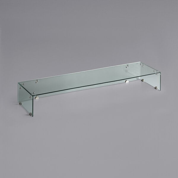 An Avantco glass sneeze guard on a gray surface.