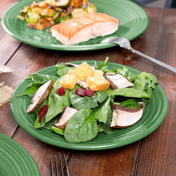 A Fiesta® luncheon plate with salad, fish, and a fork on a table.