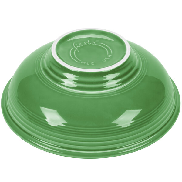 A close-up of a green Fiesta pedestal serving bowl with a white rim.