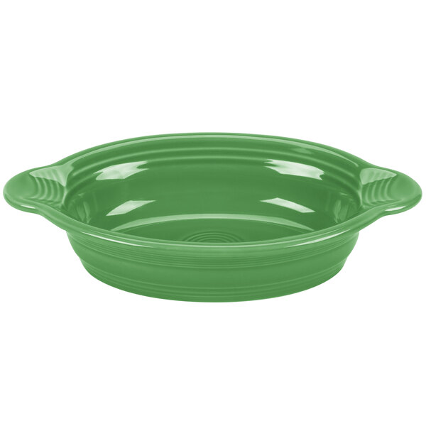 A green oval casserole dish with a white interior and handles.