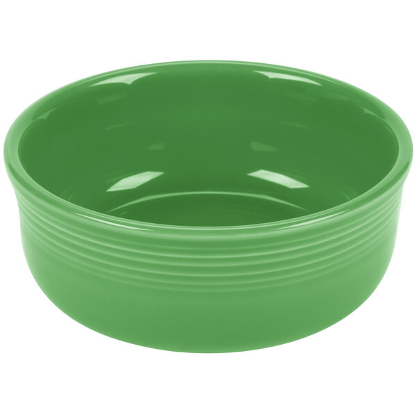 A green bowl with a white interior and a handle.