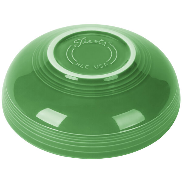 A green bowl with a white rim on a green surface.