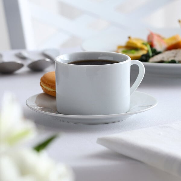 A white 10 Strawberry Street porcelain cup on a saucer with a drink in it.