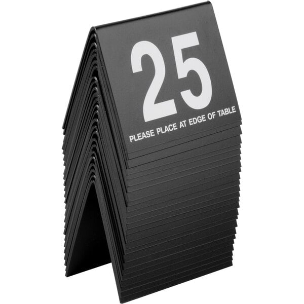 A stack of black Cal-Mil table number tents with white numbers on the front.
