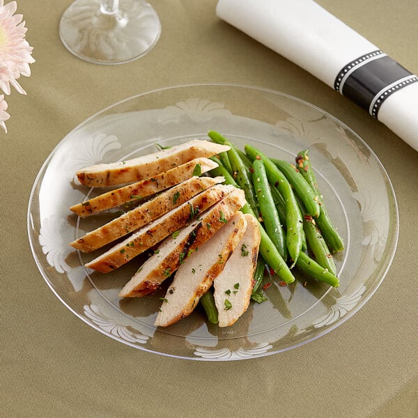 A WNA Comet clear plastic plate with sliced chicken and green beans on it.