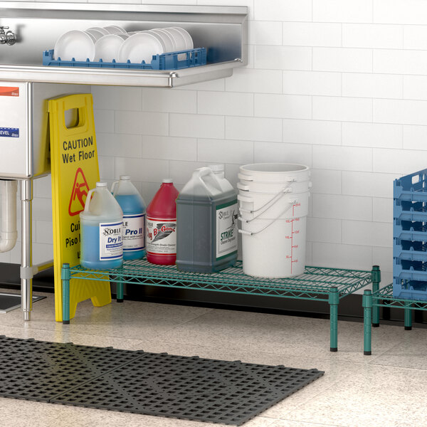 A Regency green wire shelf holding white bottles with blue liquid over a sink.
