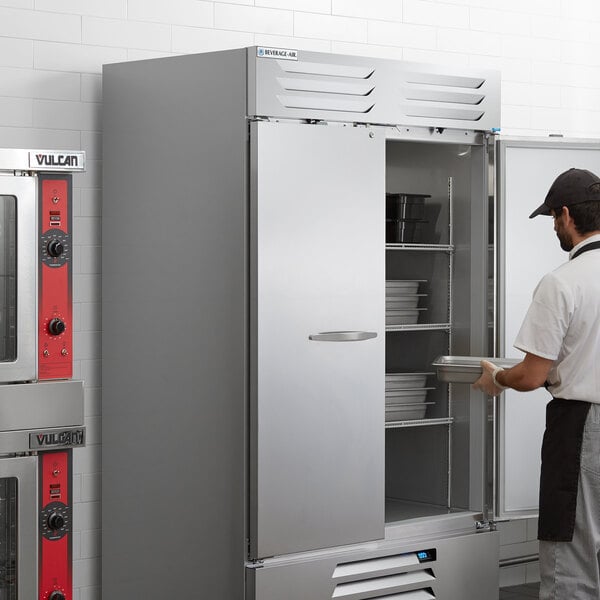 A man opening a Beverage-Air Vista Series reach-in freezer with solid doors.