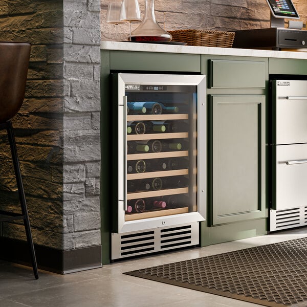 A stainless steel commercial wine cooler with a glass door built into a kitchen cabinet.