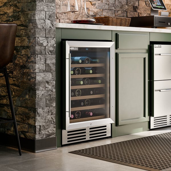 A stainless steel commercial wine cooler with a glass door built into a kitchen cabinet.