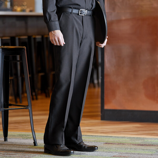 A man in a black suit and black customizable dress pants stands in a room.