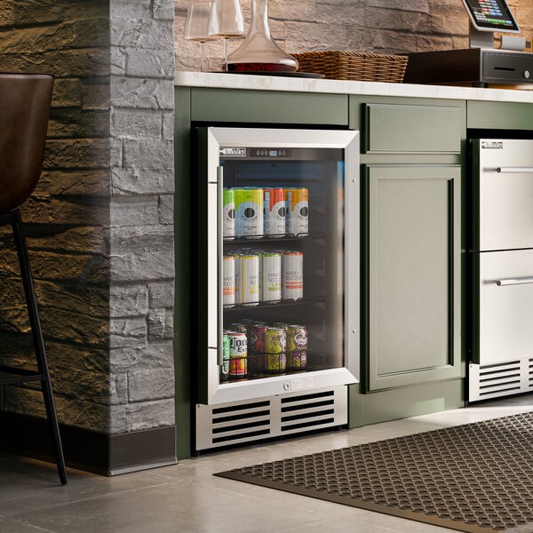 A stainless steel beverage cooler with a glass door built into a kitchen cabinet.
