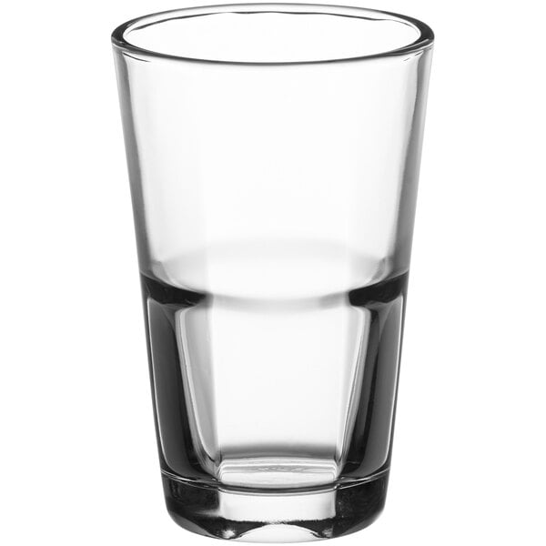 An Anchor Hocking stackable beverage glass filled with a clear beverage on a white background.