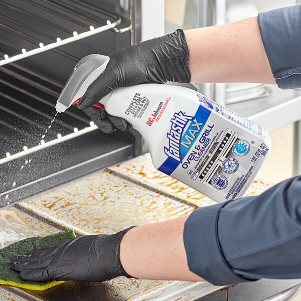 A person in gloves spraying a grill with SC Johnson fantastik Max Oven and Grill Spray.