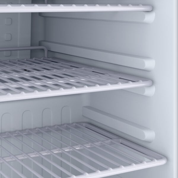 An empty interior of a small refrigerated merchandiser with wire shelves.