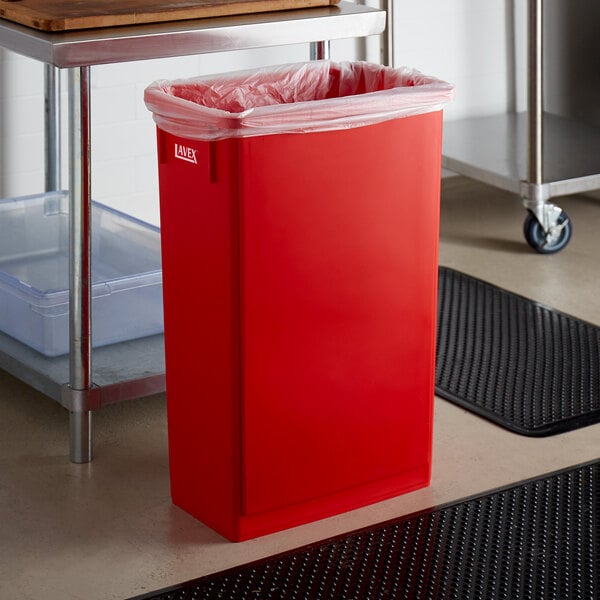 A red rectangular Lavex Slim Trash Can on a kitchen floor.