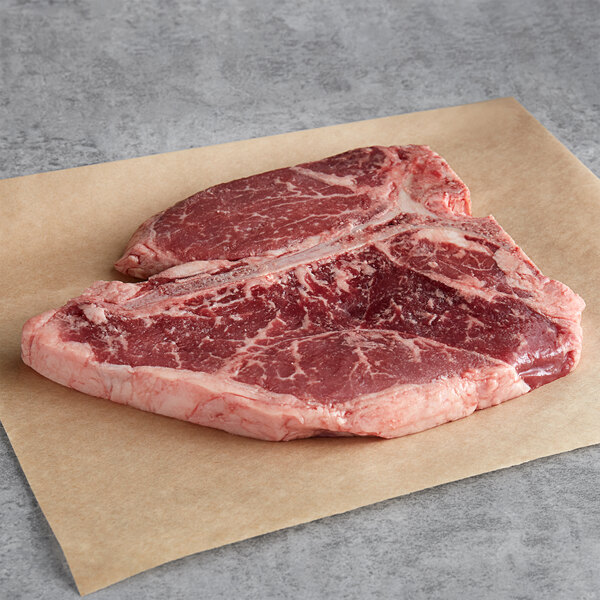 A raw Warrington Farm Meats porterhouse steak on a paper.