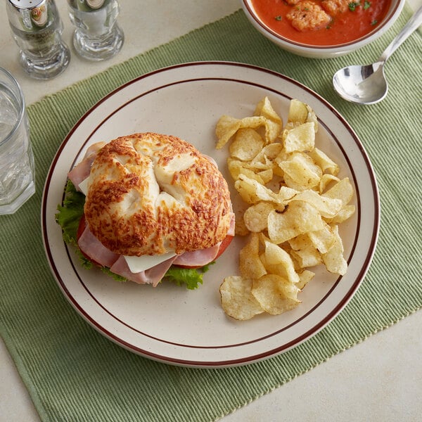 A brown speckled Acopa stoneware plate with a sandwich and chips on it.