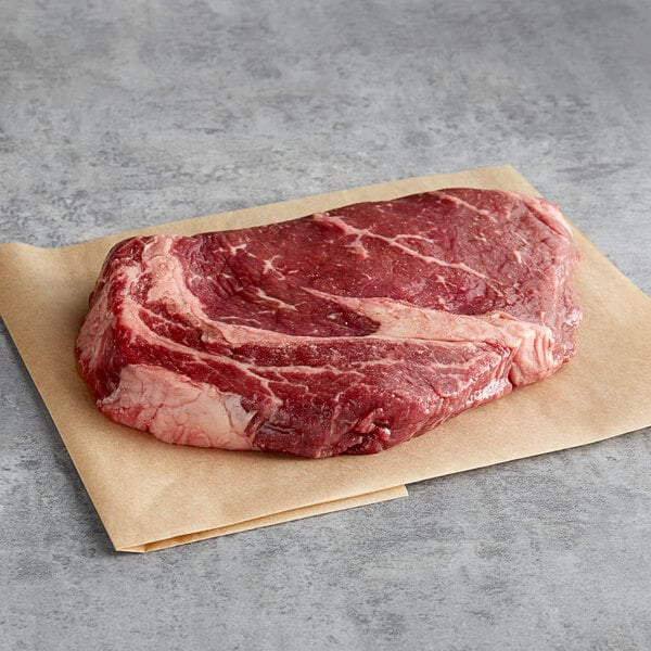 A piece of raw Warrington Farm Meats Delmonico steak on a paper.