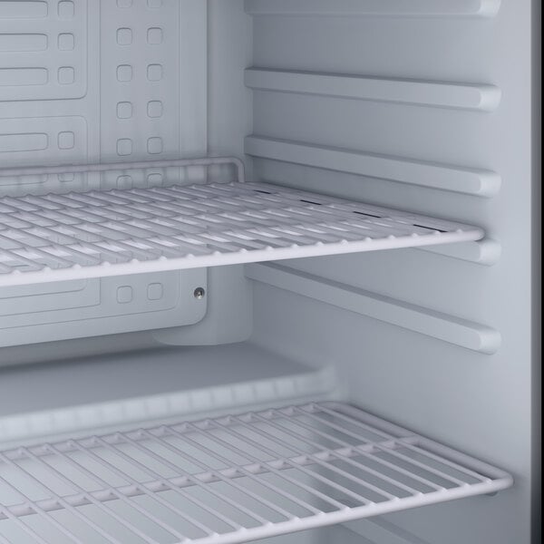 An empty interior of a refrigerated merchandiser with adjustable wire shelves.