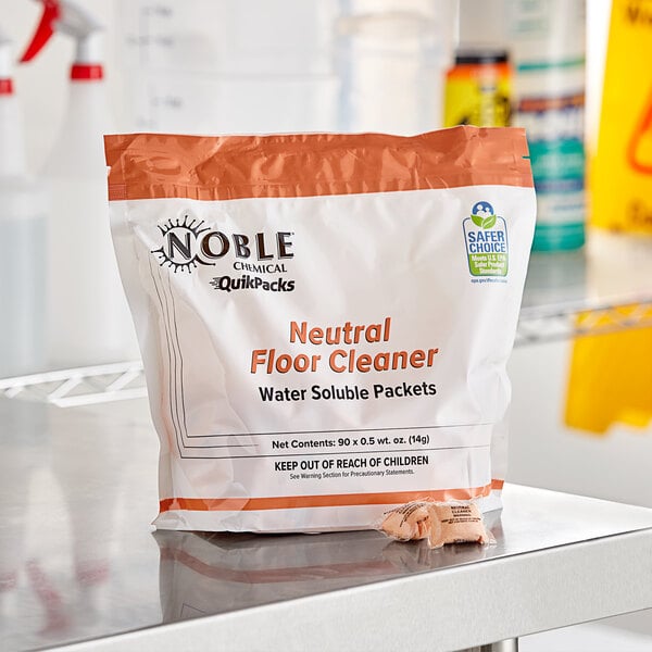 A tub of Noble Chemical QuikPacks concentrated neutral floor cleaner with a plastic strip on the counter.