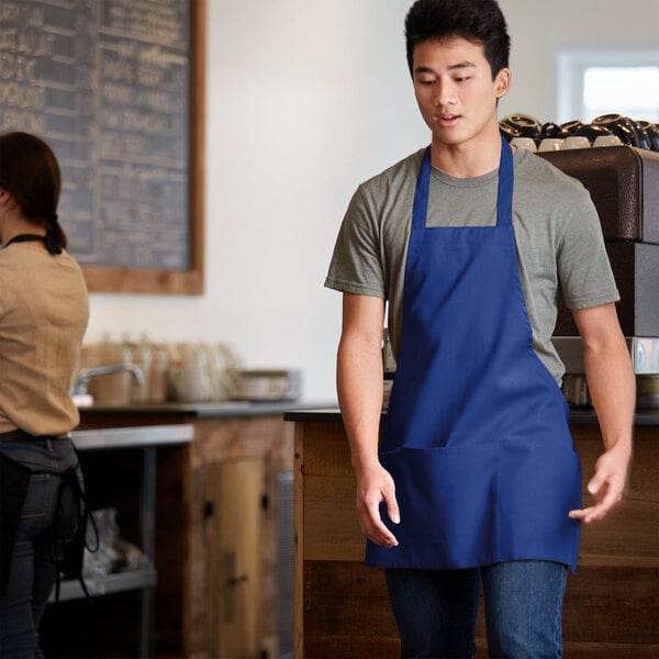 A man wearing a Choice royal blue apron with three pockets over a white shirt.