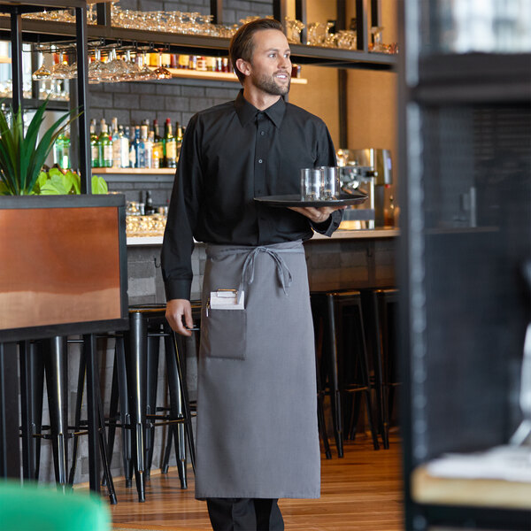 A man in a black shirt and gray Choice bistro apron holding a tray.