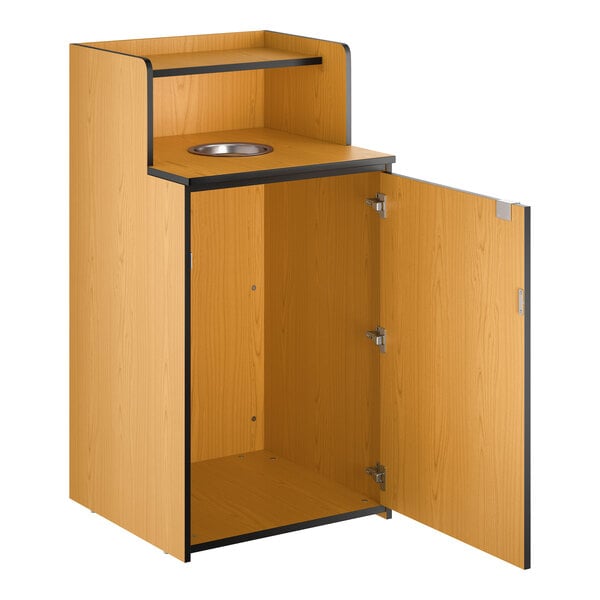 A wooden waste receptacle enclosure with a drop hole, tray shelf, and an open cabinet door.