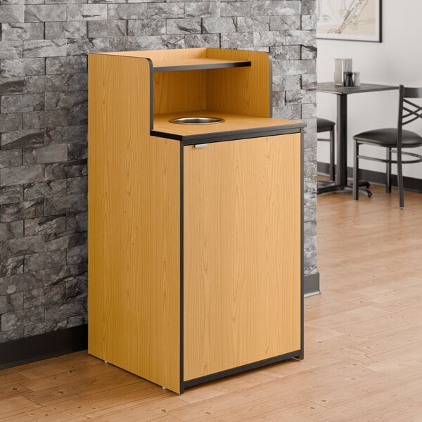 A natural wood waste receptacle enclosure with a drop hole and tray shelf designed to hold up to 32 gallons.
