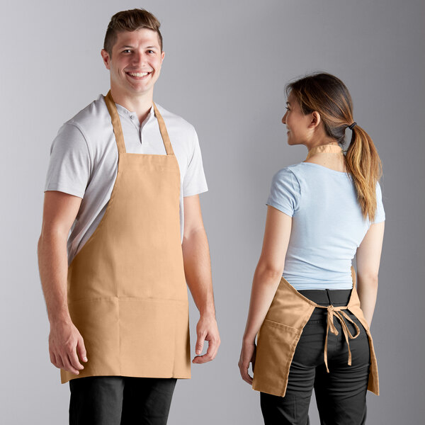 A man and woman wearing Choice khaki poly-cotton bib aprons.