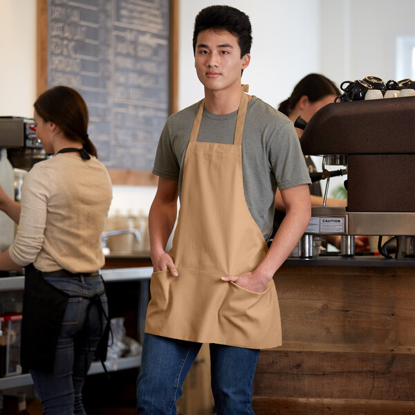A man wearing a Choice khaki bib apron with 3 pockets.
