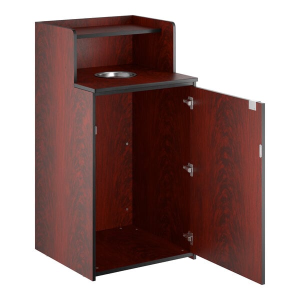 A mahogany waste receptacle enclosure with a drop hole, tray shelf, and an open cabinet door.