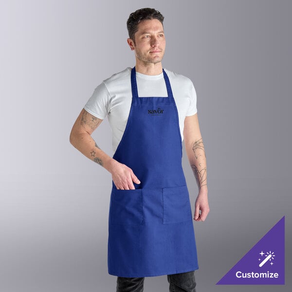 A royal blue poly-cotton standard bib apron with two front pockets, worn by a person.