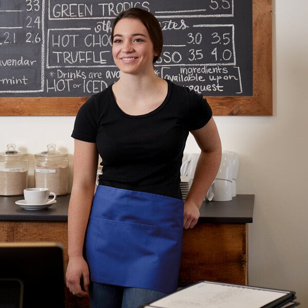 A woman wearing a black shirt and a royal blue apron with three pockets.