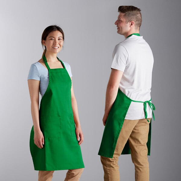A man and woman wearing Choice Kelly Green adjustable bib aprons.